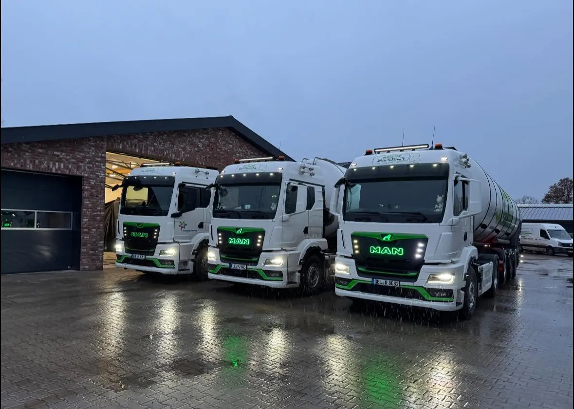Drei MAN-Tankzüge mit grüner Beleuchtung im Regen vor der Halle